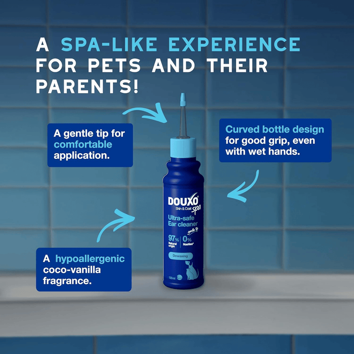 Blue tiled background with a blue bottle of Douxo Ultra-safe ear cleaner with aqua blue nozzle. Text above states 'A spa-like experience for pets and their parents!' Below are blue boxes with white text 'A gentle tip for comfortable application, Curved bottle design for good grip, even with wet hands, A hypoallergenic coco-vanilla fragrance.'
