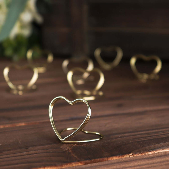 Gold heart-shaped ring holder on wooden surface.