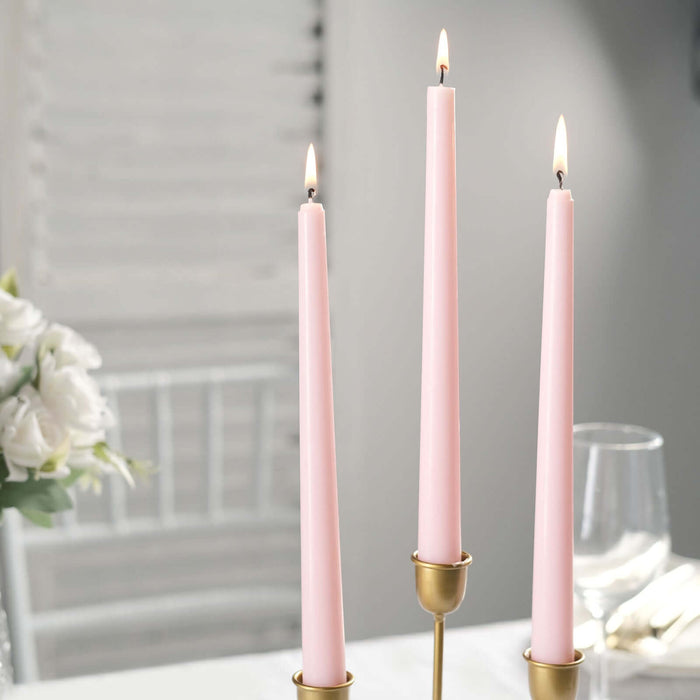 Pink taper candles in gold holders, elegantly lit for ambiance.