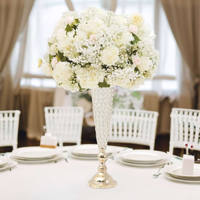 Elegant white floral centerpiece in a sparkling vase on a dining table.