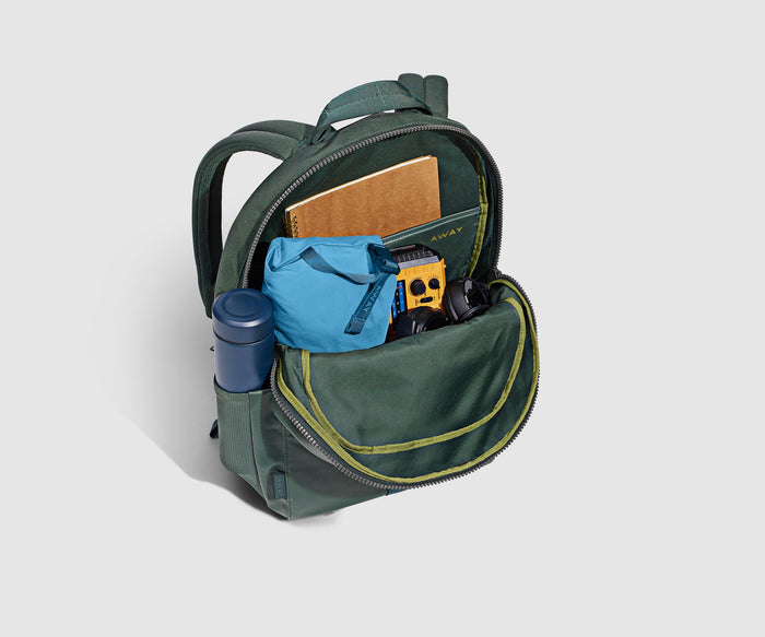 Main compartment packed with an organizational pouch, notebook, and headphones. Water bottle in the exterior water bottle pocket
