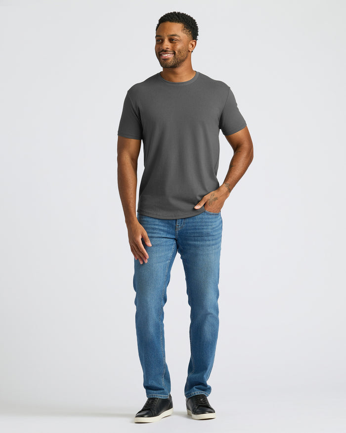 Man wearing a gray t-shirt and blue jeans on a white background