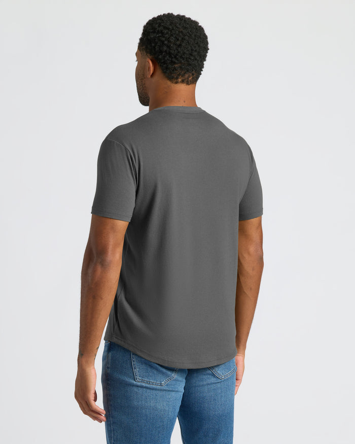 Man wearing a gray t-shirt and blue jeans on a light gray background