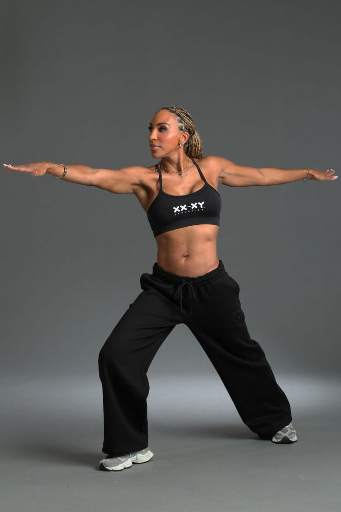 Woman in black athletic wear posing against a gray background || black