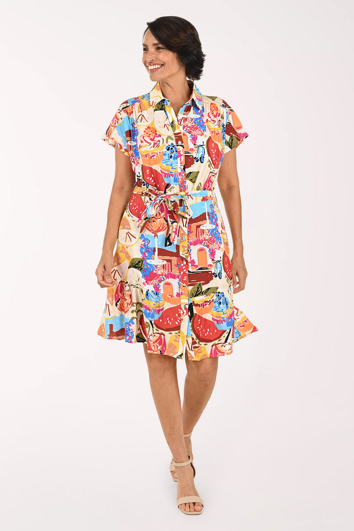 A woman modeling a short-sleeve collared shirt dress with a colorful abstract print, featuring a tie waist and ruffled hem, set against a plain white studio background.