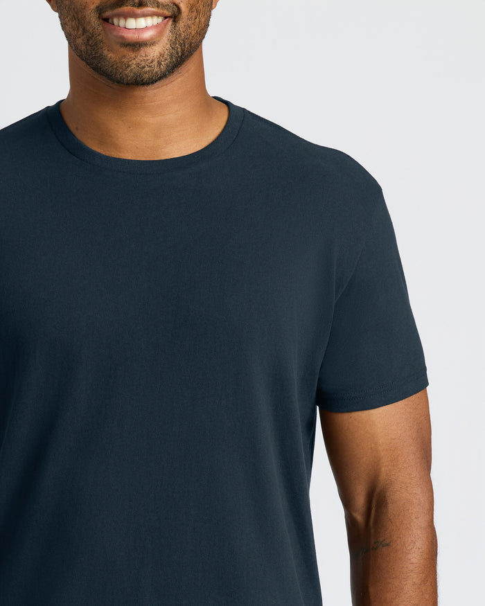 Man wearing a plain navy blue t-shirt on a light gray background