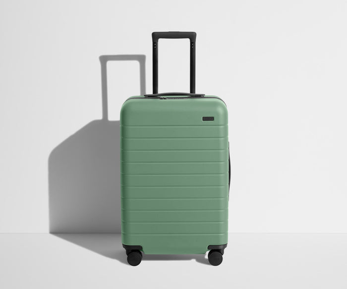 Front product view of The Bigger Carry-On suitcase in Sea Green with raised handle