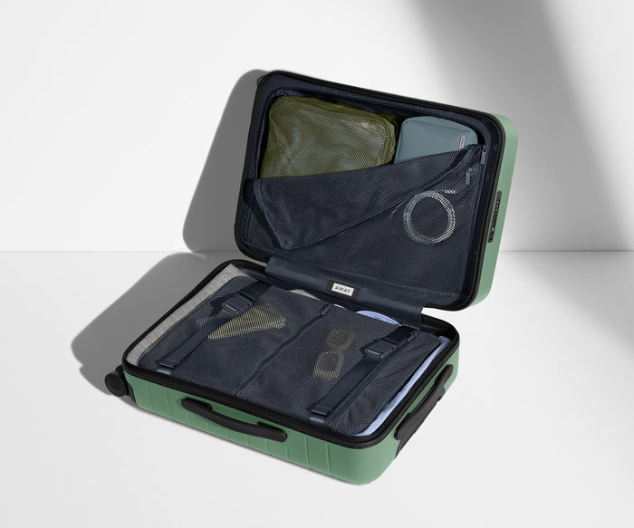 The Bigger Carry-On suitcase in Sea Green shown open on its side and packed with Away's packing organizers to show capacity and the interior compression system, designed to help you pack more in
// 
Our signature interior compression system allows you to stay more organized. Paired with The Insider Packing Cubes.