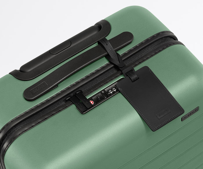 The Bigger Carry-On suitcase in Sea Green shown shown from above highlighting TSA-approved combination lock and recycled leather luggage tag
//
All of our suitcases come with a leather luggage tag. Add up to three letters to personalize yours and stand out at the baggage claim.