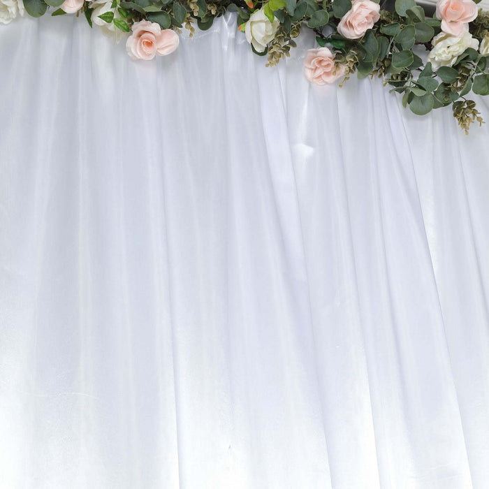 Elegant white backdrop with floral accents and soft draping.